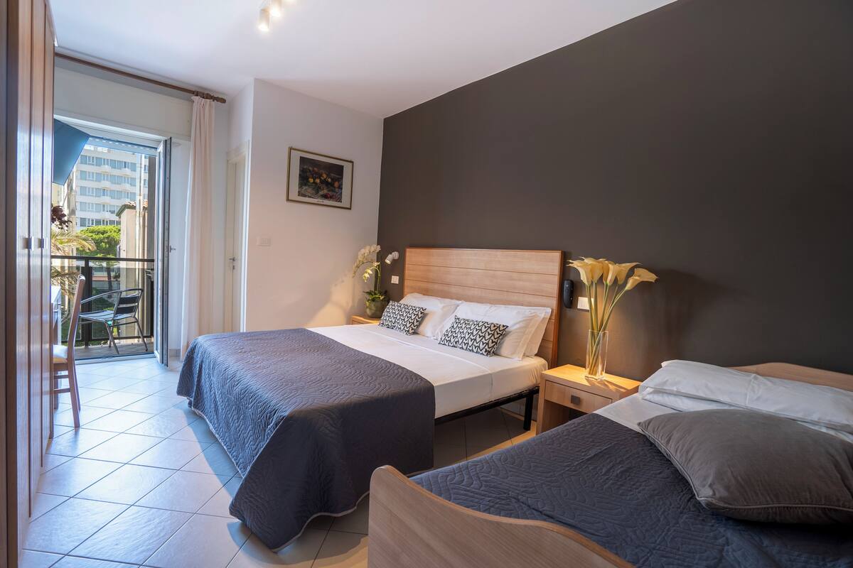 Une chambre d’hôtel avec deux lits, un balcon et une vue sur les immeubles.