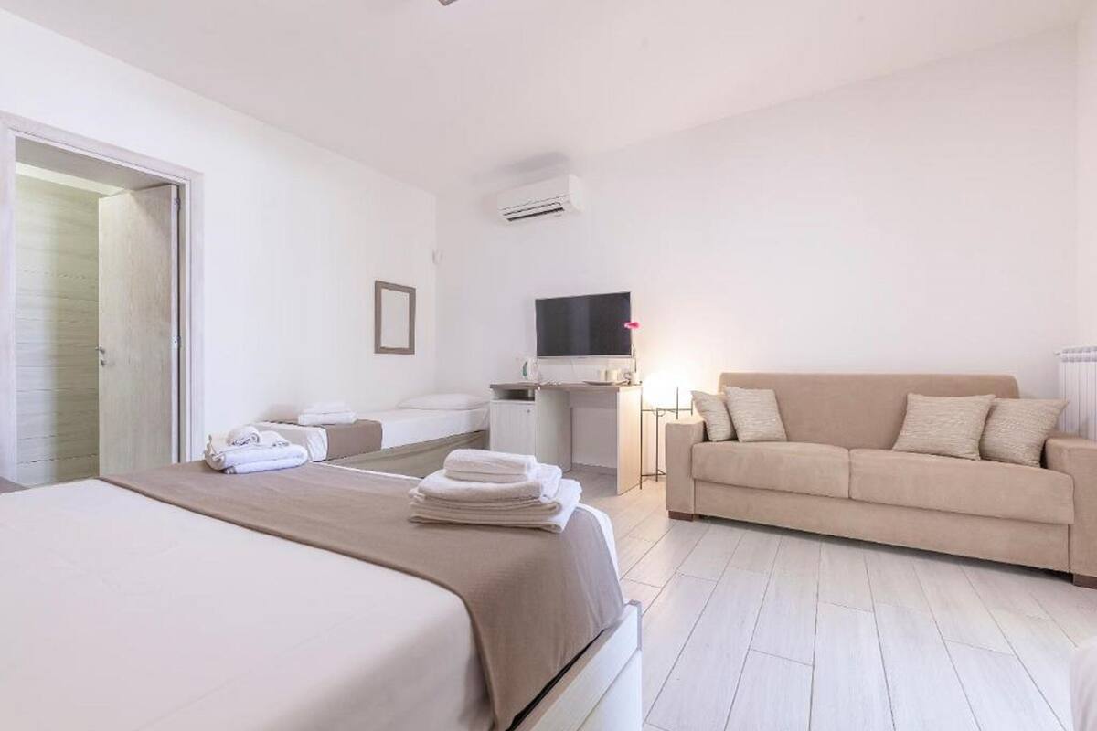 Ein Hotelzimmer mit Bett, Sofa, Schreibtisch und Fernseher.