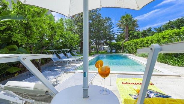 Ein Poolbereich mit Liegestühlen und einem tropischen Garten.