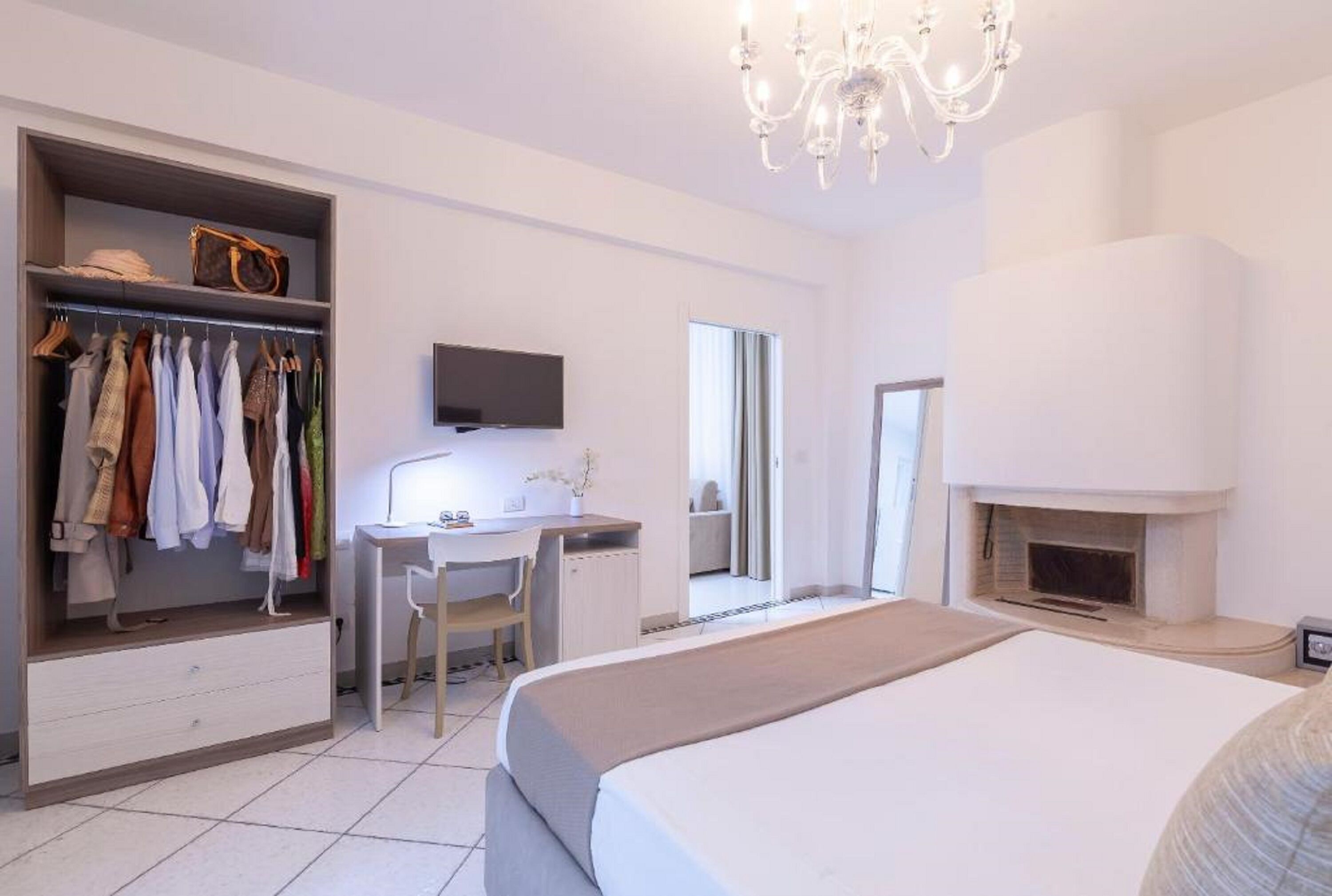 Un dormitorio con cama, escritorio, silla, armario, televisor y chimenea.