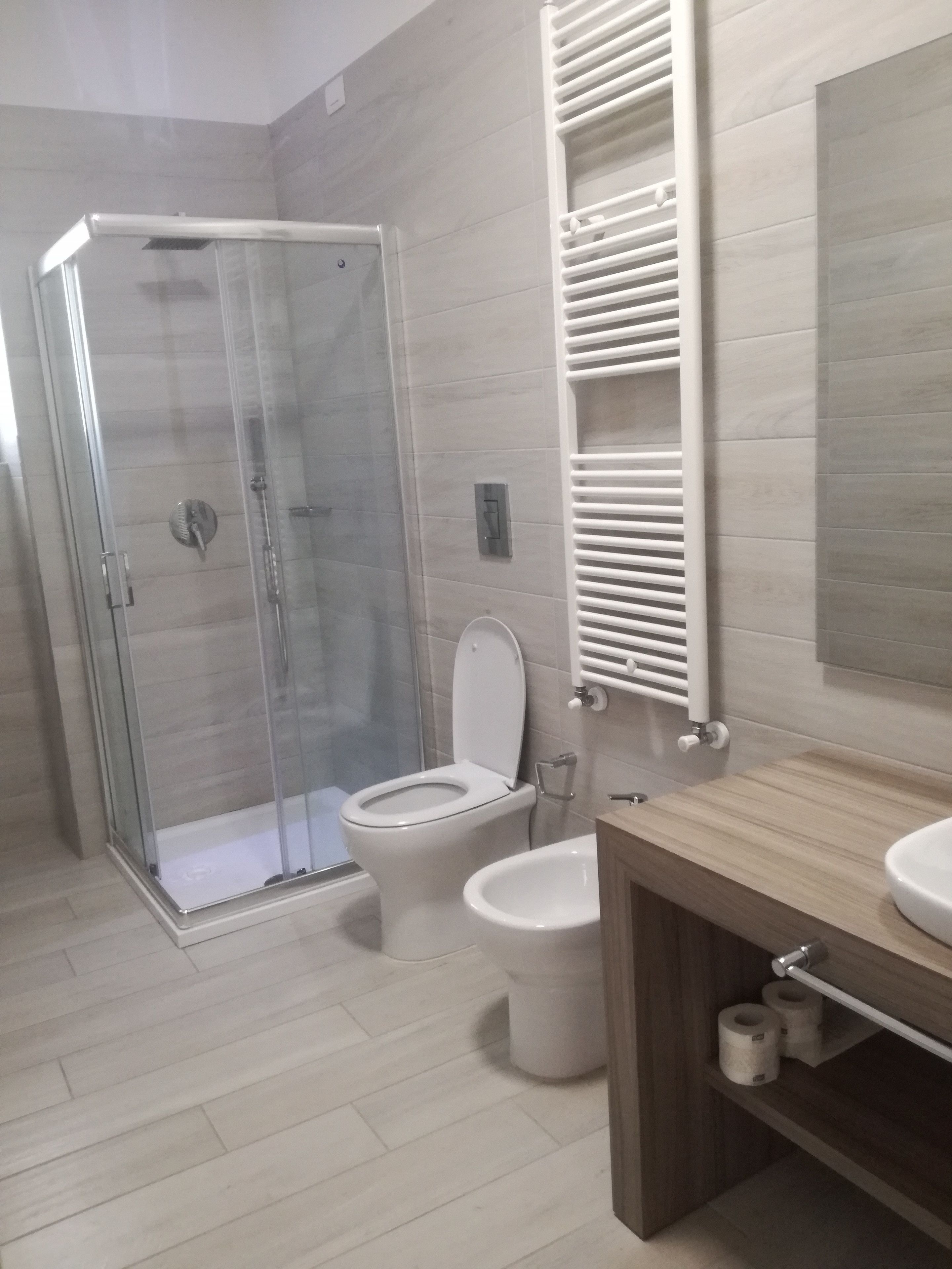 A modern bathroom with a glass-enclosed shower, a toilet, and a wooden vanity with a sink.