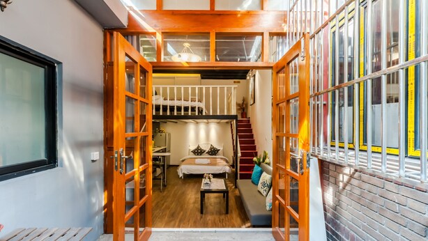 Habitación pequeña y de varios niveles con cama, escritorio y escalera.
