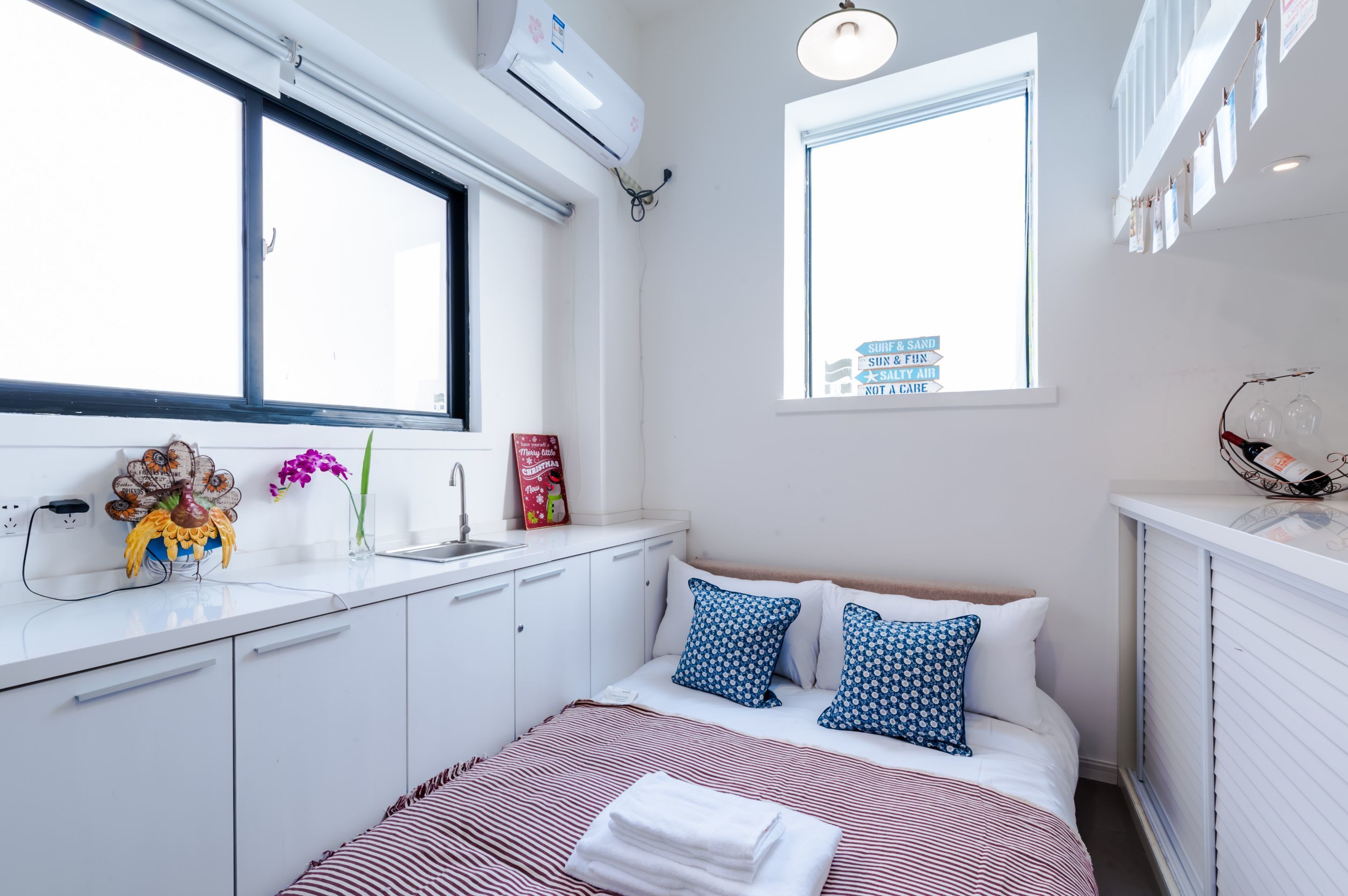 Un dormitorio moderno con una cama grande, una ventana, un aparador blanco y un equipo de aire acondicionado.