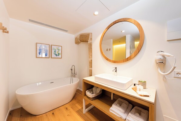 A modern bathroom with a freestanding bathtub, a wooden vanity with a sink, and a large mirror. - Forum Boutique Hotel & Spa (Alcúdia)