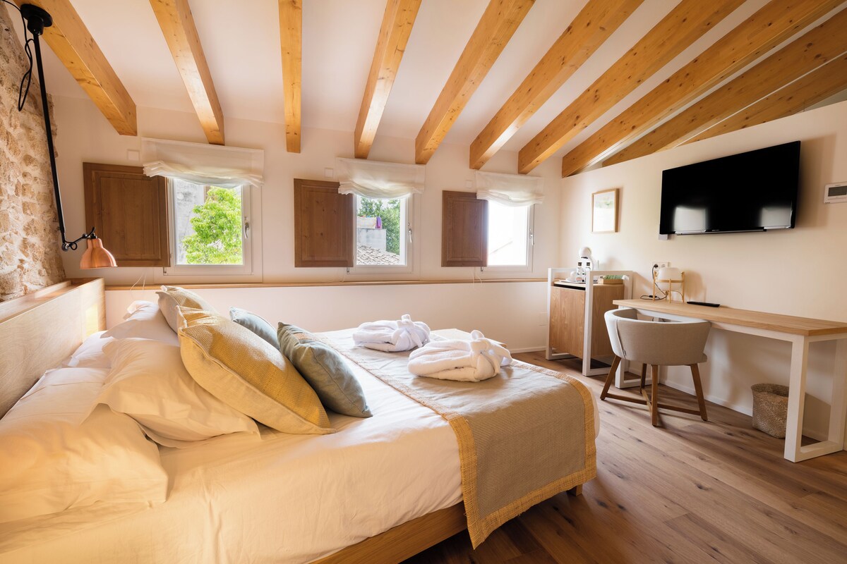 A bedroom with a bed, a desk, a chair, and a TV.