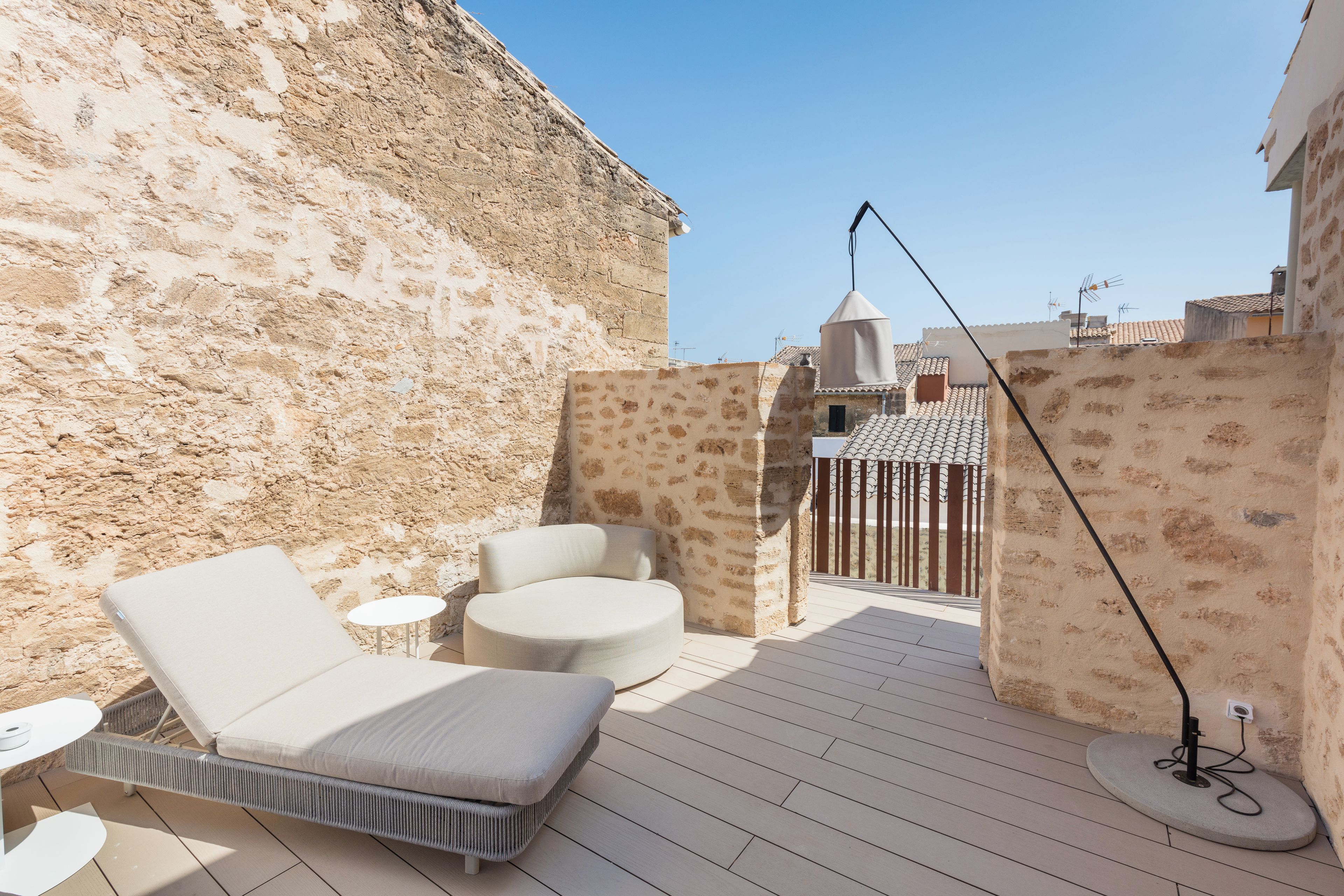 Una terraza en la azotea con una silla de descanso, un otoman redondo y una mesita.