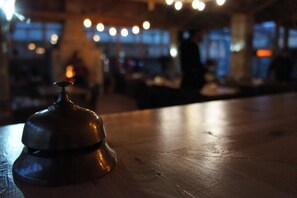 A wooden table with a bell on it, in a dimly lit indoor setting with blurred background elements. - Ormana Active Dogan Boutique Hotel (Ibradi)