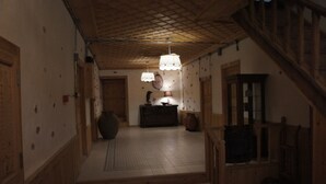 A wooden staircase leading to a room with a tiled floor, a wooden cabinet, and a hanging light fixture.