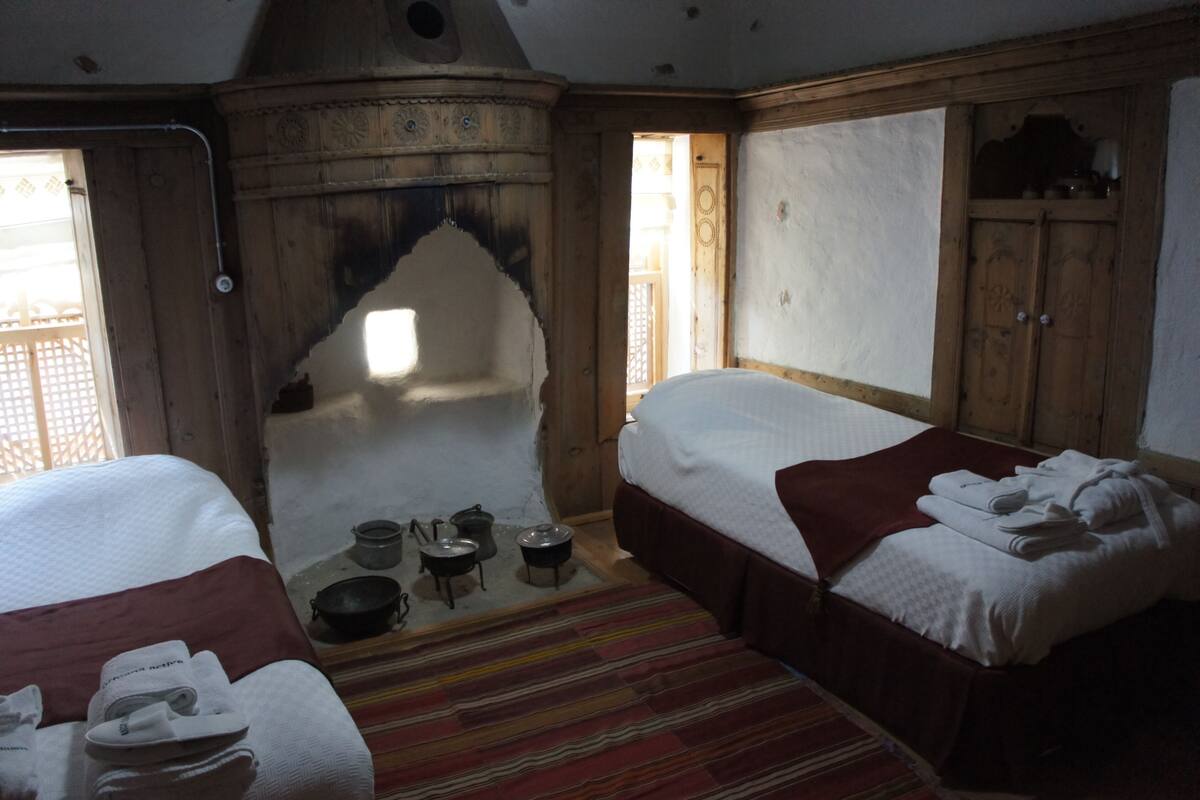 A room with two beds, a fireplace, and a view of the outside.