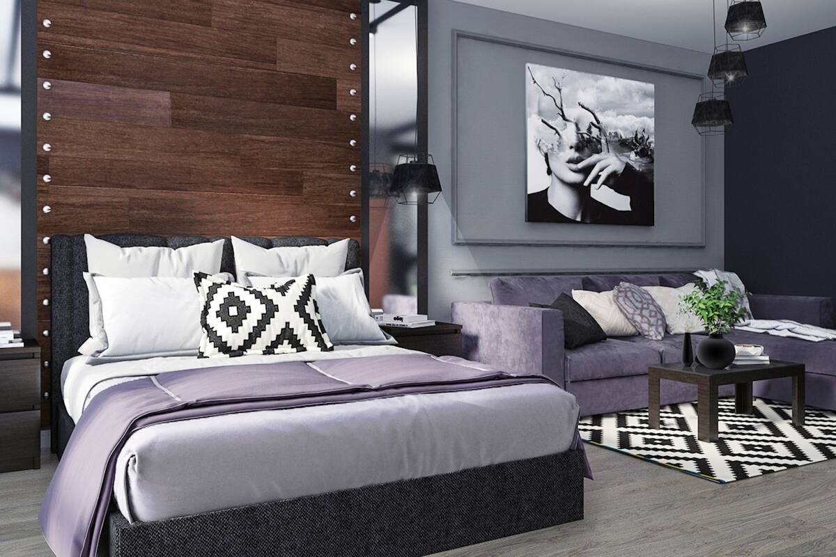 A modern bedroom with a bed, a sofa, a coffee table, and a painting on the wall.