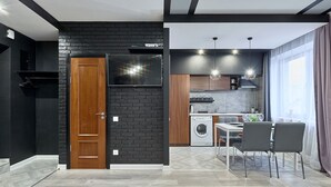 Une cuisine moderne avec un mur en briques noires, une porte en bois et un téléviseur à écran plat.