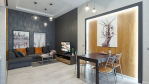 Un salon moderne avec un canapé gris, une table à manger et un téléviseur à écran plat.