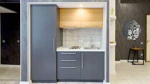Une cuisine de taille réduite avec des meubles gris, un plan de travail blanc et un évier en acier inoxydable.