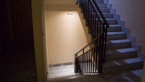 A staircase with a handrail and a light fixture on the wall. - Hostal Acuario (Galvez)