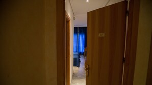 A hotel room with a wooden door, a visible room number, a bed, and a blue curtain. - Hostal Acuario (Galvez)