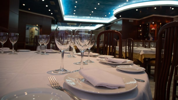 A restaurant setting with tables set for dining, featuring clear glassware and plates. - Hostal Acuario (Galvez)