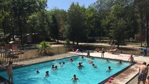 A swimming pool surrounded by a wooden deck and a wooden fence. - Camping L'Art De Vivre (Chateauneuf-du-Pape)