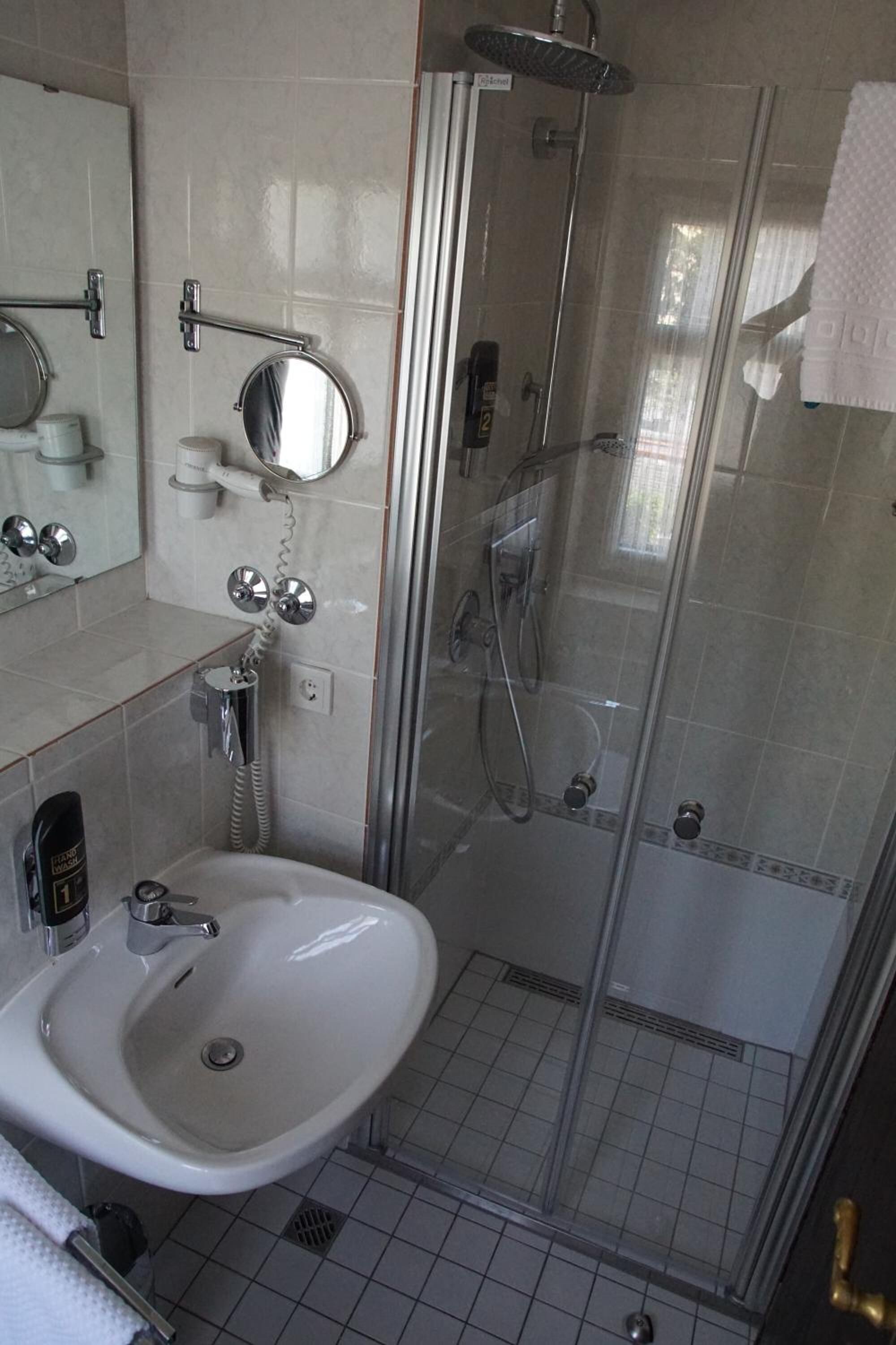 A modern bathroom with a glass-enclosed shower, a white sink, and a mirror above it.