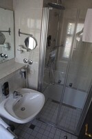 A modern bathroom with a glass-enclosed shower, a white sink, and a mirror above it.