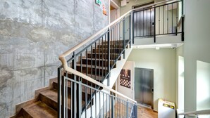 A multi-level interior with a staircase, a concrete wall, and a door with a poster. - Ratusz B&B (Gdansk)
