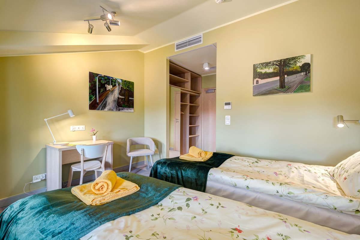 A hotel room with two beds, a desk, a chair, and a closet.