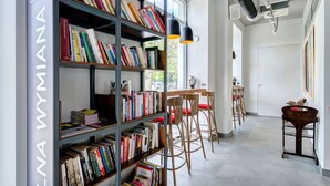 A modern library with bookshelves, wooden chairs, and a dining area with a white table and chairs. - Ratusz B&B (Gdansk)