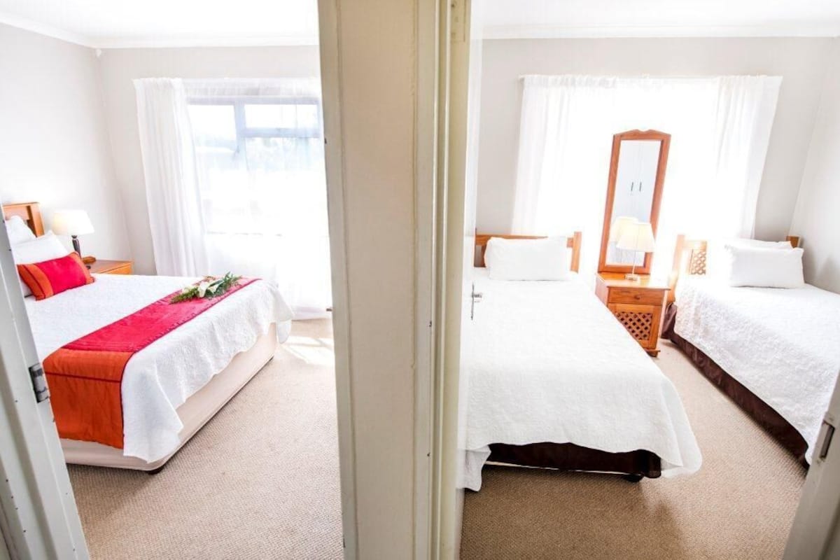 Habitación de hotel con dos camas, un espejo grande y vistas al exterior.