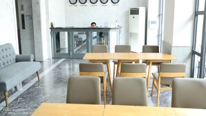 A hotel lobby with a reception desk, a sofa, and a dining area with chairs and a table. - Fide Hotel (Ho Chi Minh City)