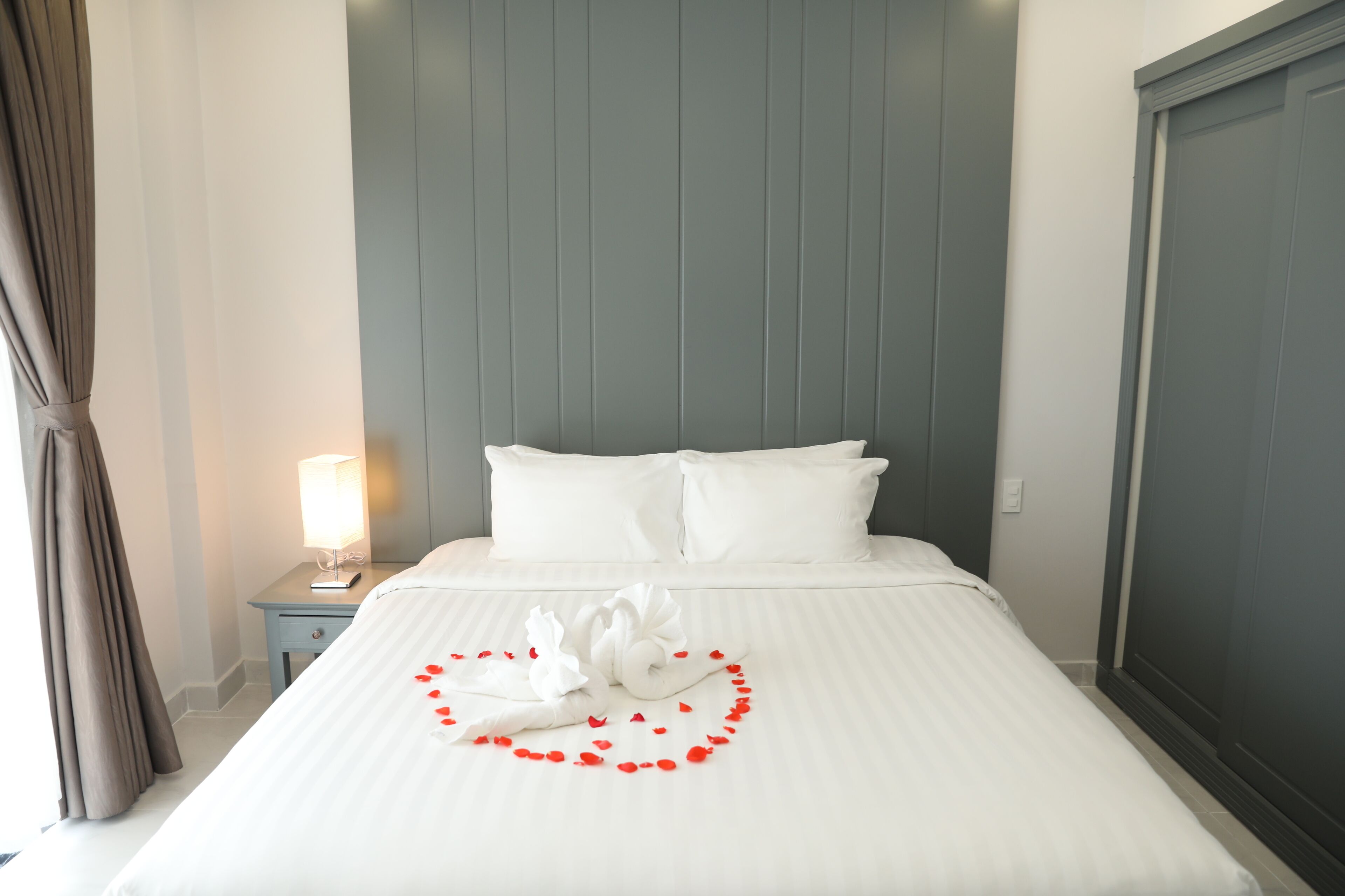A neatly made bed with white linens, a pillow, and a decorative swan made of fabric on the bedspread.