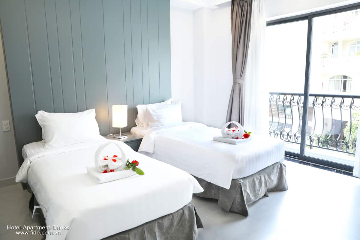 Quarto de hotel com duas camas, uma janela ampla com vista para o exterior e uma varanda.