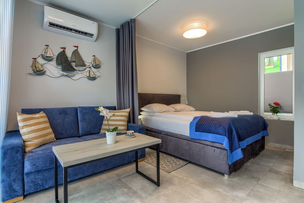 Ein modernes Schlafzimmer mit Bett, Sofa, Couchtisch und einer Wand-Klimaanlage.