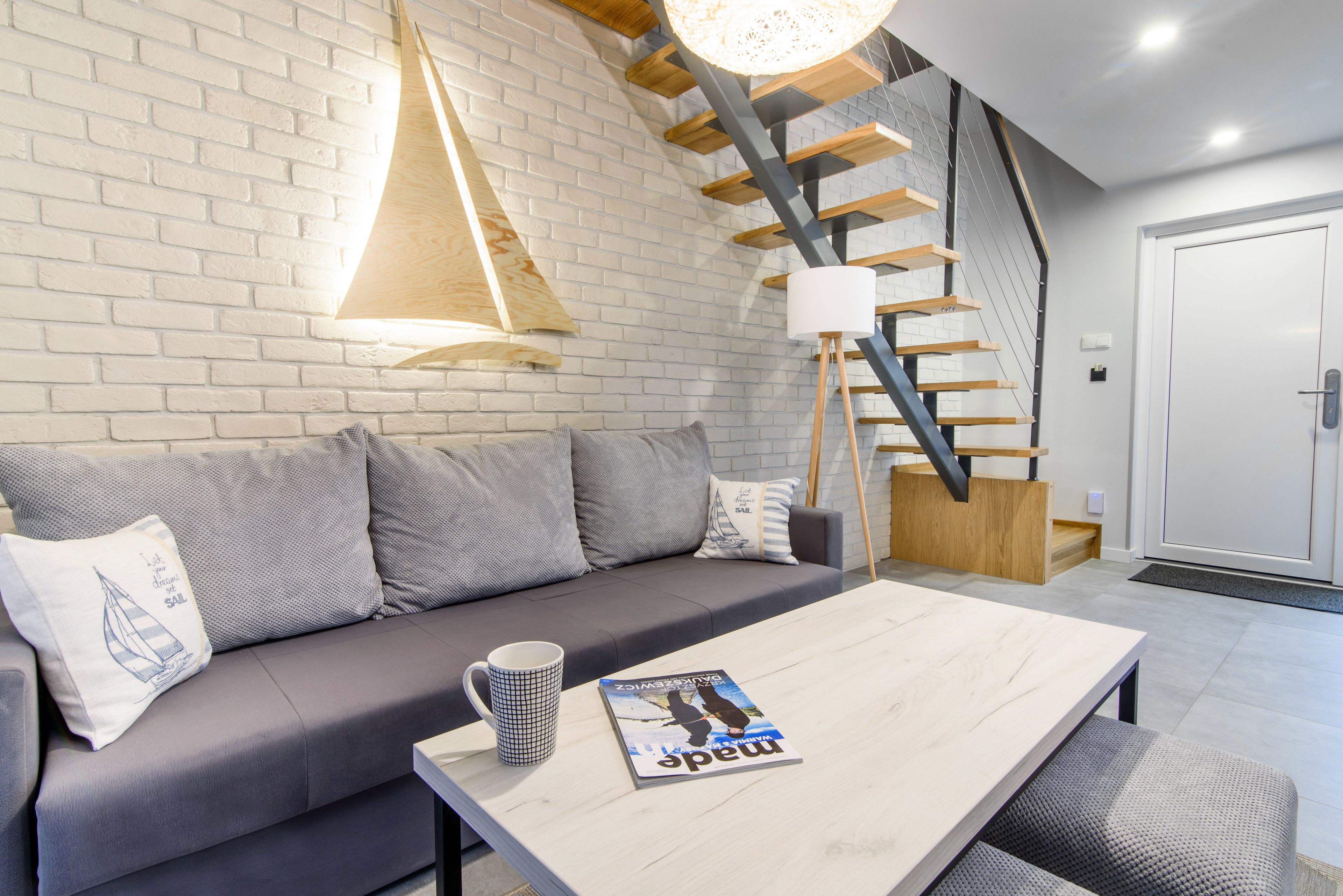 A modern living room with a grey sofa, a wooden coffee table, and a magazine.