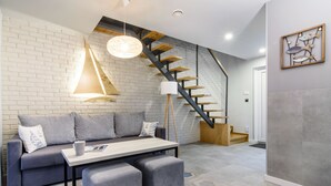 Una sala de estar moderna con un sofá gris, una mesita de centro y una escalera con escalones de madera.