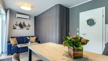 Una sala de estar moderna con un sofá, una mesa de madera, una planta en maceta y una puerta con un ventanal circular.
