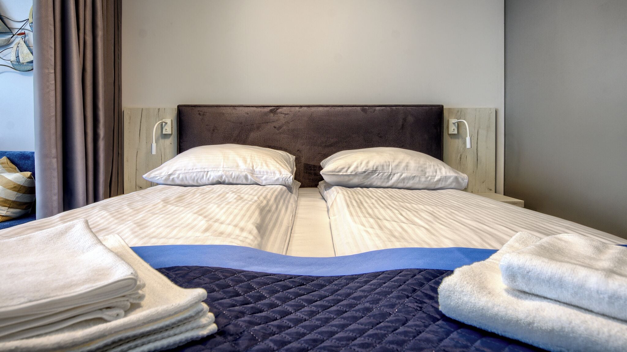 Un lit double avec une couverture matelassée, deux oreillers et une pile de serviettes pliées.