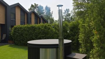 A hot tub with a chimney, surrounded by a well-maintained lawn and a brick patio.