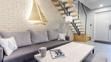 A modern living room with a grey sofa, a wooden coffee table, and a magazine.