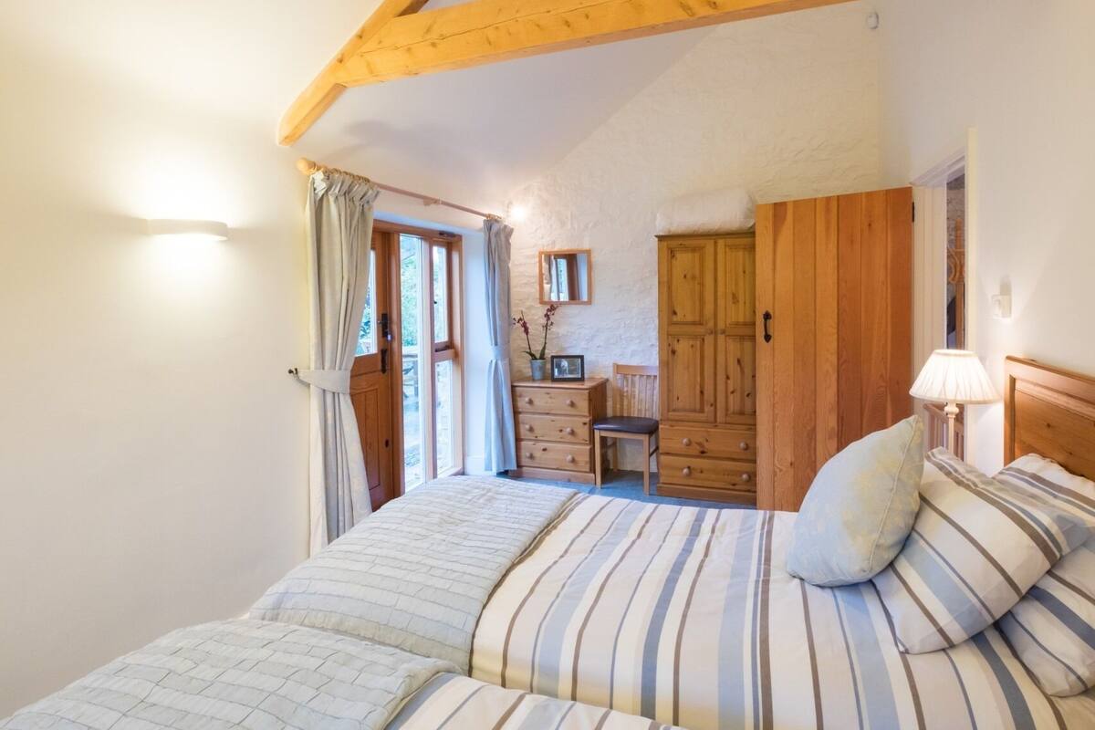 A bedroom with a bed, a dresser, a mirror, and a door leading to a balcony.