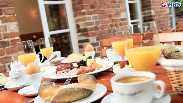 A breakfast table with plates of food, glasses of orange juice, and a cup of coffee. - Alte Schule (Reichenwalde)