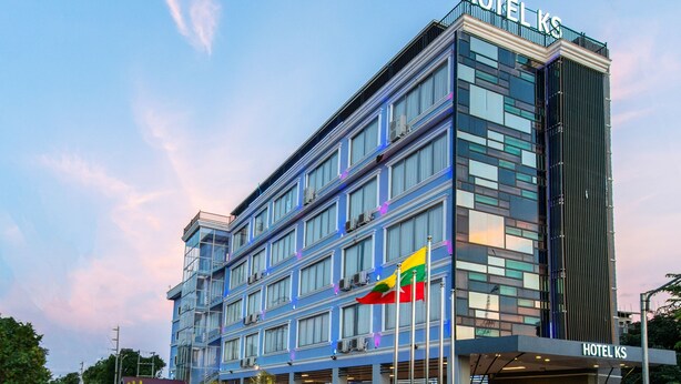 En moderne hotelbygning med et tydeligt skilt med teksten "HOTEL KS" og et løve-emblem.