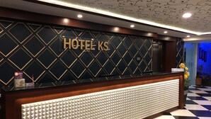 En hotelreception med en væg i geometrisk mønster, et receptionsskilt og en indtjekningsdisk.
