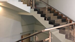 En moderne trappe med glasgelændere og et metalgelænder, der fører til en etage ovenpå.