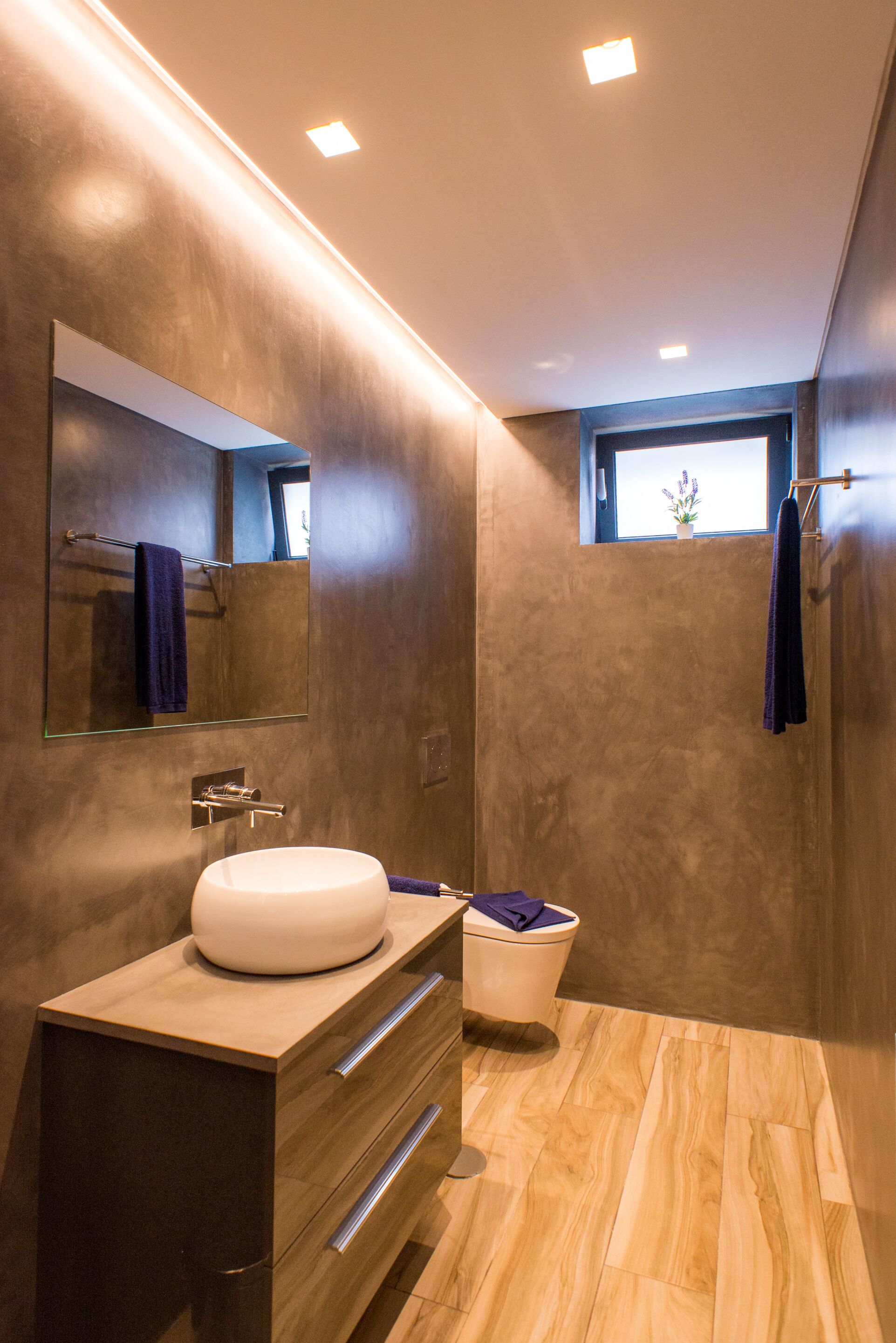 A modern bathroom with a large mirror, a sink, a toilet, and a shower area.