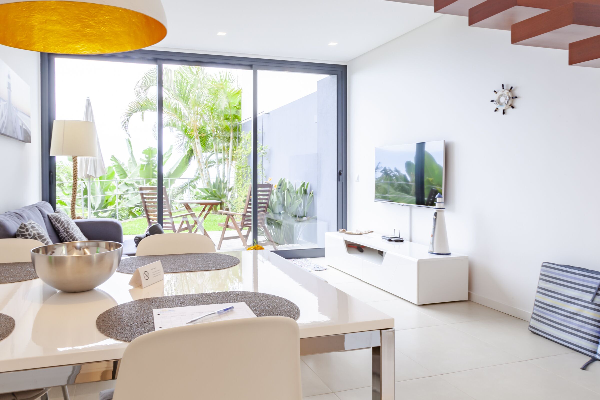 A modern living room with a dining area, large windows, and a TV.