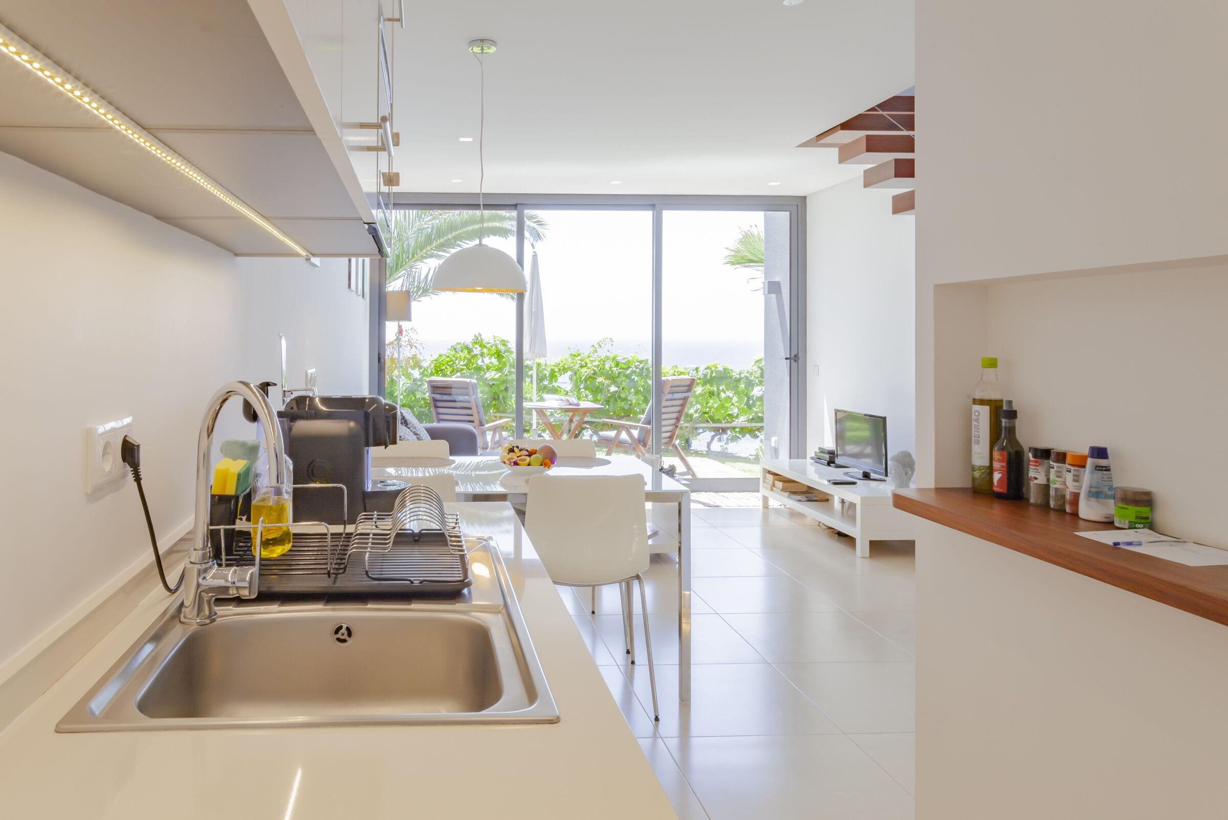 Une cuisine moderne équipée d’un évier, d’un coin repas et offrant une vue sur l’extérieur.