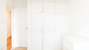 Quarto branco com um guarda-roupa grande, uma porta e piso coberto de carpete.