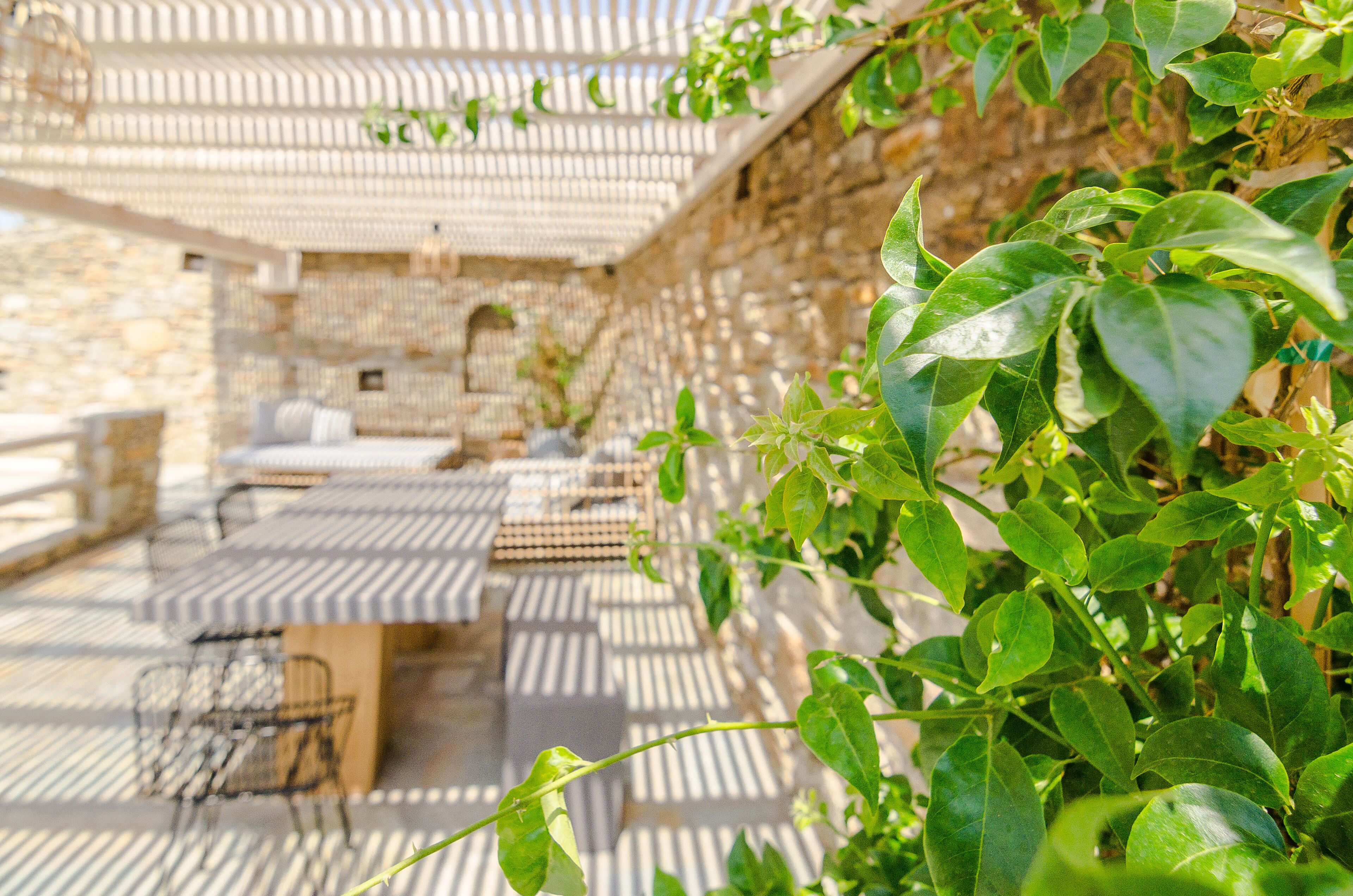 An outdoor patio with a table and chairs, a stone wall, and greenery.