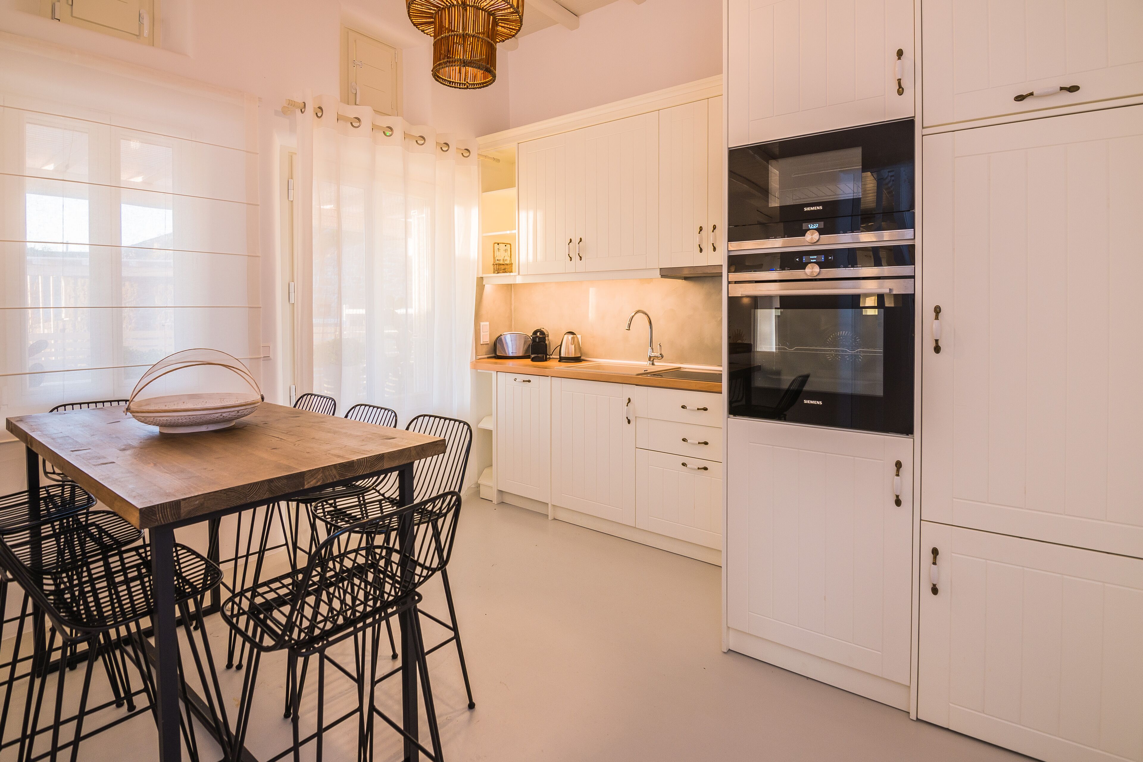 Una cucina moderna con mobili bianchi, un tavolo di legno e sedie nere.