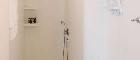 Un baño pequeño y blanco con ducha, inodoro y lavabo.