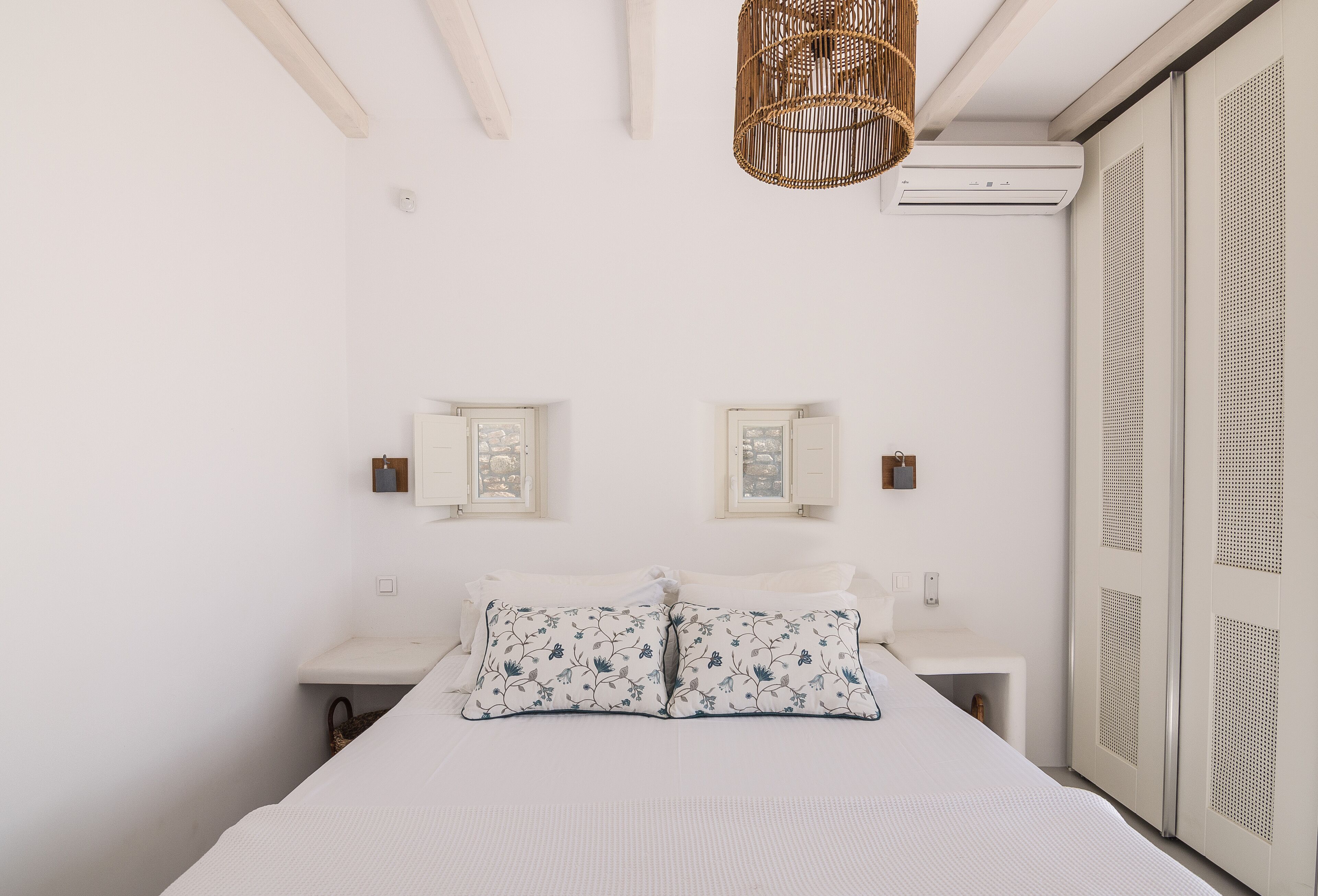 A minimalist bedroom with a bed, bedside tables, and a wardrobe.